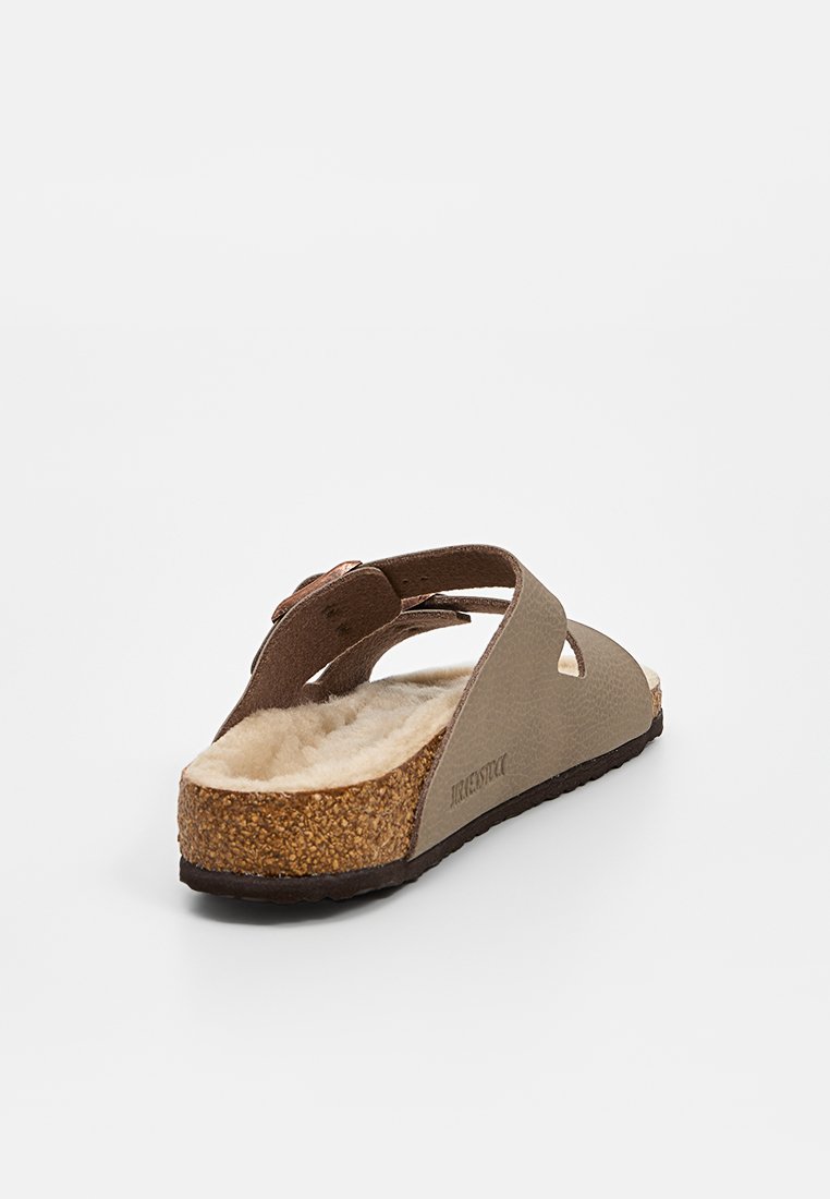 Sandale à semelle en liège brun avec une semelle intérieure beige douce, deux sangles réglables et un matériau supérieur texturé de couleur brun clair.