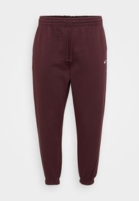 Burgundské tepláky s elastickým pásom a šnúrkou, so zúženými nohavicami a malým bielym logom na hornej stehne.