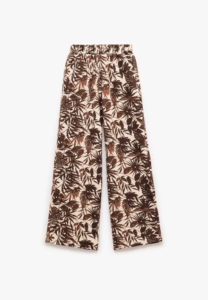 Pantalones de pierna ancha con un fondo crema y patrones de hojas y plantas en marrón, cinturilla elástica y una textura de tela suave.