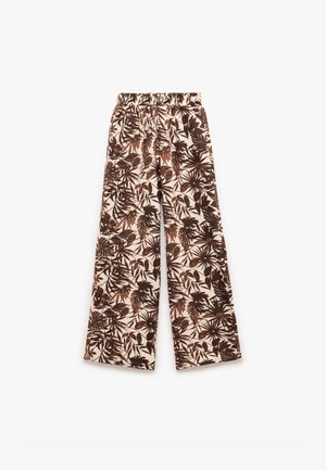 Pantalones de pierna ancha con un fondo crema y patrones de hojas y plantas en marrón, cinturilla elástica y una textura de tela suave.