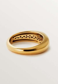 Anillo de metal en tono dorado con un exterior liso y redondeado. El interior presenta pequeñas perforaciones espaciadas uniformemente. Acabado pulido sin acentos adicionales.