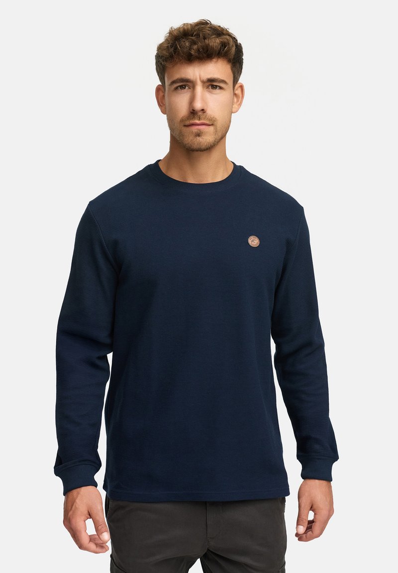 Mørkeblå langærmet sweatshirt lavet af tekstureret stof med ribbet halsudskæring og et lille rundt logo på brystet.