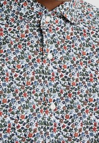Camicia a bottoni floreale con base bianca, fiori multicolori in rosso, blu e verde, colletto classico e bottoni perla.