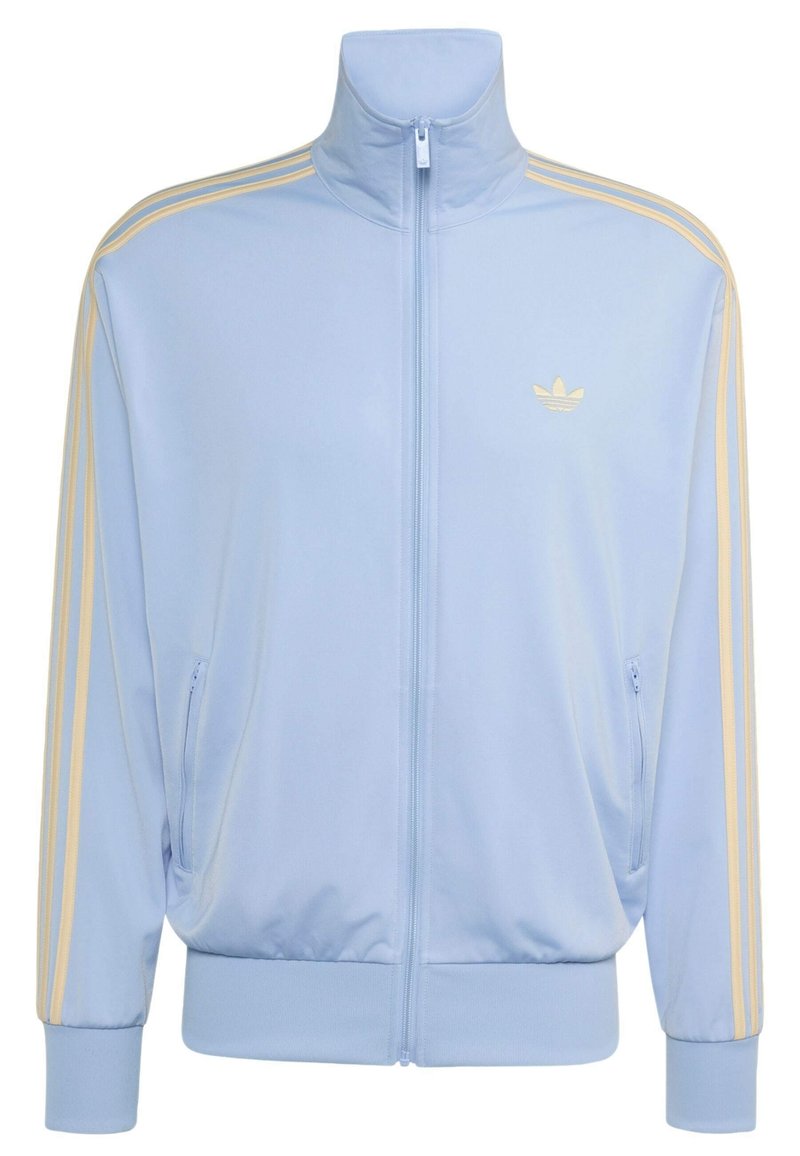 Light blue zip-up track jacket with high collar, beige triple stripes on sleeves, and beige Adidas trefoil logo on chest.