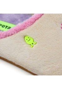 Chausson beige flou avec une bordure en peluche rose, décoré d'un petit accent de poisson vert vif et d'un intérieur en tissu violet.