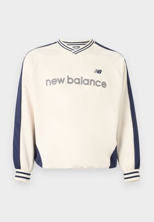 Cream and navy long-sleeve New Balance sweatshirt with striped cuffs and collar, and "new balance" text across the chest.
