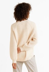 Beżowy sweter prążkowany o luźnym kroju, z okrągłym dekoltem i długimi rękawami, z detalem kieszeni po bokach z tyłu.