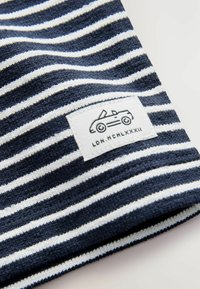 Marineblåt og hvidt stribet stof med en struktureret finish, der har et label med en dekoration af en konvertibel bil samt teksten "LDN. MCHLXXXII."