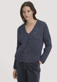 Marinefarbener Strickpullover mit V-Ausschnitt, gerippter Struktur und langen Ärmeln. Entworfen mit einer lockeren Passform und subtilen Farbvariationen.