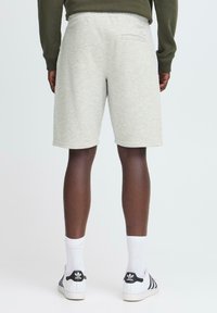 Pantalones cortos de algodón grises con cintura elástica, que cuentan con un bolsillo trasero, combinados con calcetines blancos y zapatillas clásicas en blanco y negro.
