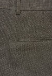 Tissu gris tissé des pantalons avec une surface texturée. Comprend une poche arrière unique avec un design en fente.