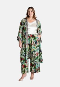 Kimono floreale con motivi verdi, rossi e blu, caratterizzato da un bordo a strisce zebrate in contrasto. Abbinato a pantaloni floreali a gamba larga e top di raso.