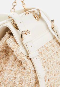 Kremowa i beżowa torba z plecionki z teksturowanym ciałem z tkaniny, gładkimi akcentami ze skóry, złotymi elementami wykończenia oraz paskiem z ogniwami łańcucha.