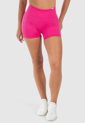 Heldroze sportshorts met een hoge tailleband, een gladde textuur en een aansluitend ontwerp, gecombineerd met witte veterschoenen.