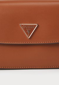 Borsa in finta pelle marrone con texture, dotata di un logo metallico triangolare, caratterizzata da un bordo cucito e chiusura a pattina.