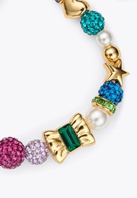 Bracelet multicolore avec des accents dorés, des pierres scintillantes en rose, violet, vert, bleu et transparent, orné d'un nœud et de détails en perle.