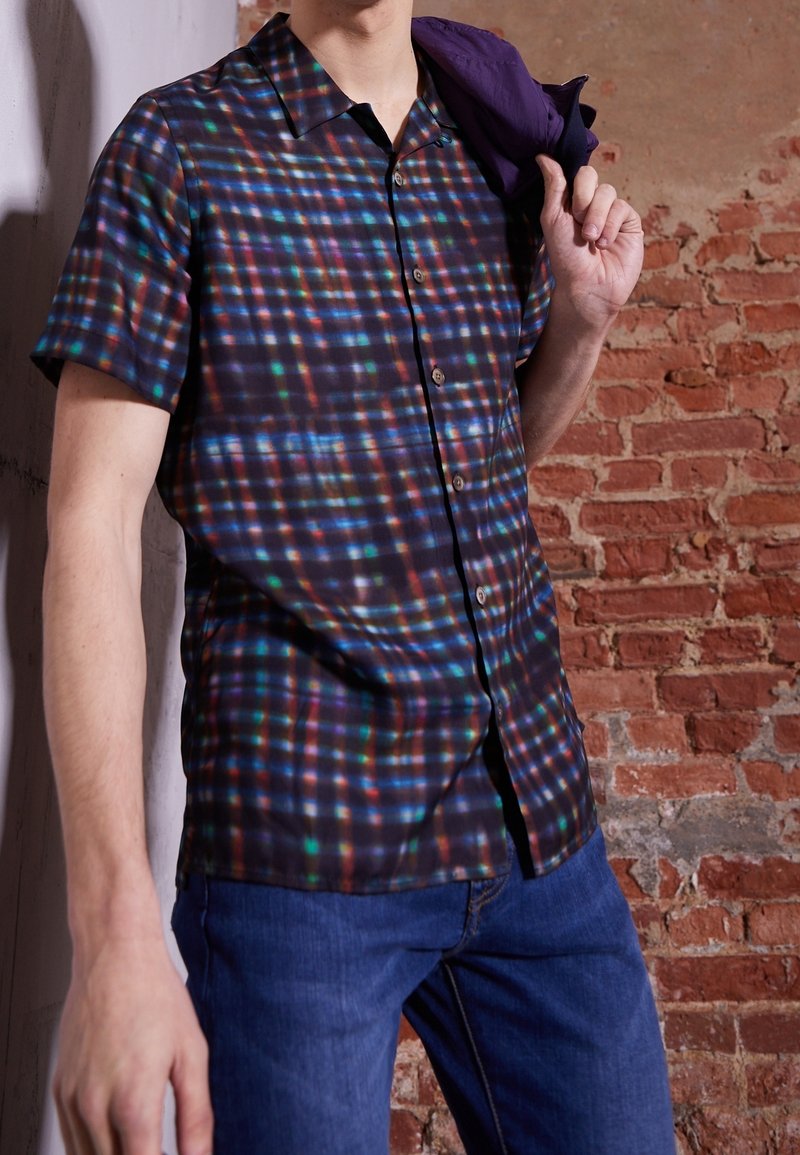 Camicia a maniche corte con bottoni in tessuto scuro con un motivo a quadri multicolore. I singoli quadrati presentano tonalità di blu, verde e rosso.