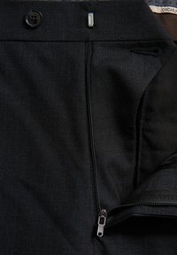 Schwarze Hose aus glattem Stoff mit Knopfverschluss, Reißverschluss und schräge Taschen mit kontrastierendem Innenfutter.