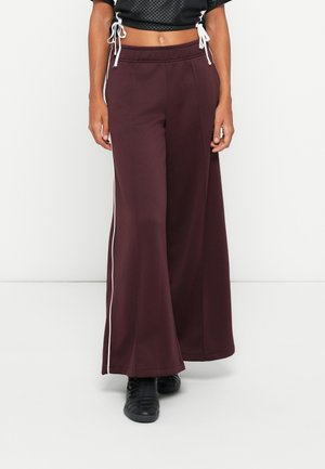 Bordeaux kleurige wijde broek van zachte stof, met een witte zijstreep en een elastische tailleband met trekkoord voor aanpassing.