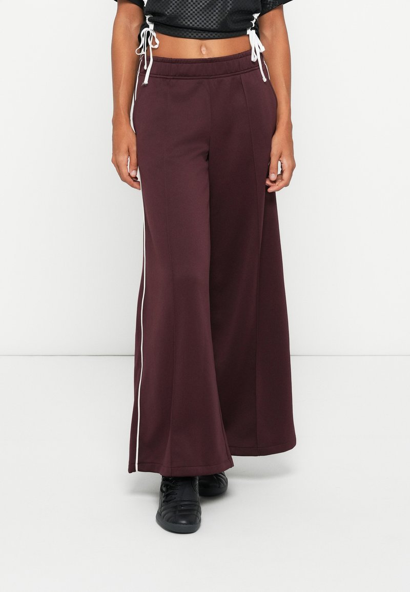 Tamsiai raudoni plačios kojos kelnes, pagamintos iš minkštos medžiagos, su balta šonine juostele ir elastingu juosmeniu su raišteliu reguliavimui.