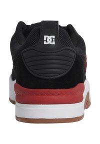 Black sneaker with a mesh and suede upper, red accents, white midsole, and a rubber outsole. Features a prominent logo on the back.