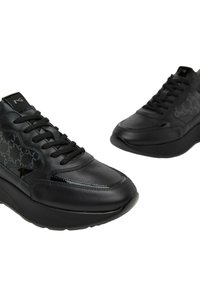 Sneaker in pelle nera con design texturizzato, forma curva e suola spessa. I lacci e i dettagli con il marchio completano il look moderno.