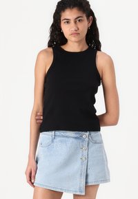 Svart ribbestrikket tank topp kombinert med et lys blått denimskjørt pyntet med rhinestones og med knappelukking i siden.