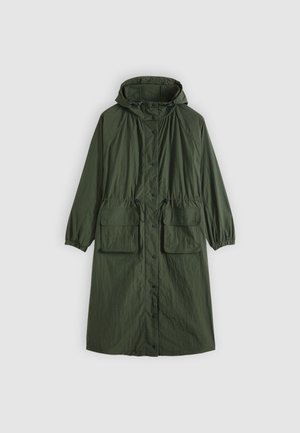Imperméable léger vert olive avec capuche, deux poches avant et fermeture par boutons. Présente des poignets élastiques et une taille à cordon de serrage pour un ajustement modulable.