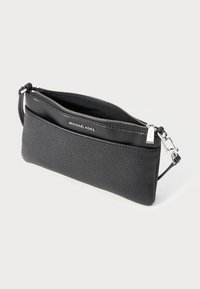 Crna kožna clutch torbica s teksturiranim tijelom, glatkom gornjom trakom, zatvaranjem na zip i odvojivom rukohvatu. Uključuje detalj s logotipom branda.