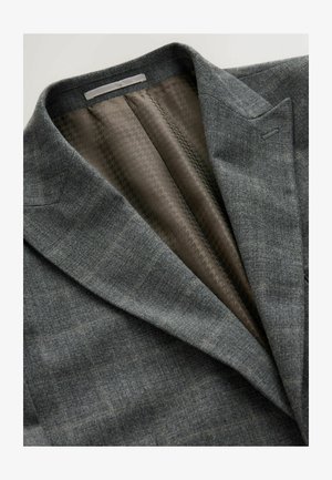 Pilkos plaid švarkas su notch tipo apykakle, turintis tekstūruotą rudą pamušalą. Sukurtas pritaikytas siluetas su struktūruotais pečiais.