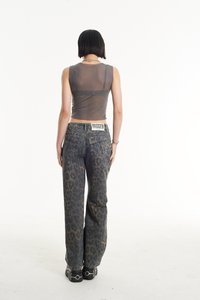 Top sin mangas gris transparente con un diseño ajustado, combinado con unos vaqueros holgados de mezclilla con estampado de leopardo. Zapatos negros con acentos metálicos completan el look.
