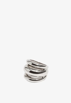 Trzy wzajemnie połączone pierścienie wykonane z polerowanego srebrnego metalu. Projekt charakteryzuje się gładkimi, zaokrąglonymi kształtami o różnych rozmiarach i szerokościach.