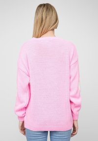 Roze gebreide trui met lange mouwen, ronde halslijn en ribbenboorden aan de manchetten en onderkant. Gekenmerkt door een gestructureerde stof en een losse pasvorm.