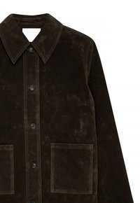 Veste en daim marron avec col pointu, fermeture à boutons sur le devant et deux poches avant. Le tissu a une texture douce et un léger brillant.