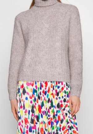 Maglione grigio chiaro a maglia con colletto alto, caratterizzato da un design a trecce. Abbinato a una gonna a fantasia multicolore.