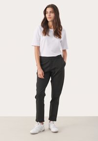 Zwarte op maat gemaakte broeken met rechte pijpen, voorzien van een knoopsluiting en zijzakken, gecombineerd met een witte T-shirt met ronde hals en witte sneakers.