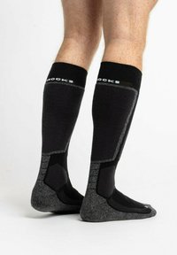 Schwarze knielange Socken mit grauen Akzenten, ausgestattet mit einem strukturierten Fußbett und verstärkten Bereichen für Langlebigkeit. Kontrastierendes Logo am Bündchen.
