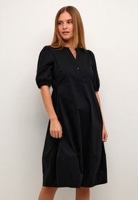 Svart knälång klänning med v-ringning, korta puffärmar, knapplist och avslappnad passform. Slät tyg med minimala designdetaljer.