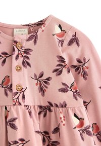 Rosa långärmad klänning med fåglar och lövmönster. Har en rundad halsringning och tre träknappar framtill.