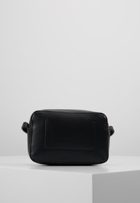 Borsa rettangolare nera in pelle con una texture liscia, caratterizzata da un sottile dettaglio di cucitura. Presenta una piccola maniglia su un lato.