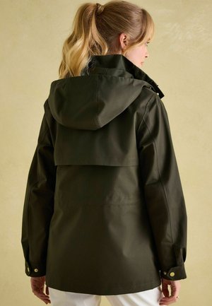 Dark green waterproof jacket with a hood, featuring a back flap, adjustable cuffs, and a relaxed fit. Smooth, lightweight fabric with minimal detailing.