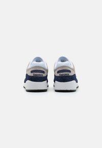 Tenisky Saucony, s vrchom z tmavomodrej a svetlošedej semišovej textílie, mäkkým textilným podšívkovým materiálom a bielou stredovou podrážkou s logom na zadnej strane.