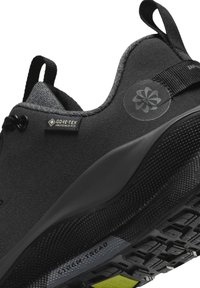 Czarny but sportowy z teksturowaną cholewką, logo Gore-Tex, amortyzowanym kołnierzem oraz wytrzymałą czarną podeszwą z jaskrawym żółtym akcentem.