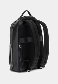 Sac à dos noir avec un extérieur en synthétique lisse et un panneau dorsal en mesh, double fermeture éclair, bretelles rembourrées et une poignée renforcée.