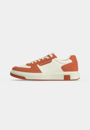 Zapatilla baja en ante crema y naranja quemado con cordones blancos y suela blanca gruesa, vista lateral.
