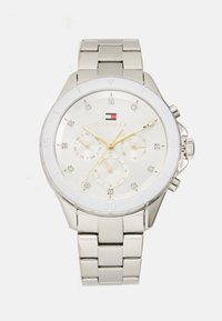 Montre en acier inoxydable argenté avec un cadran blanc, des accents dorés, trois sous-cadrans et des marqueurs en cristal. Elle dispose d'un bracelet à maillons et d'une finition polie.