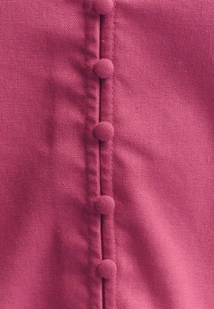 Fuchsia stof met een gladde textuur, voorzien van een rij ronde, gestructureerde knopen aan één kant en subtiele stikdetails.