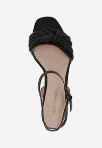 Sandale noire à bout ouvert avec une sangle texturée nouée, une fine sangle de cheville et une semelle intérieure lisse beige avec le nom de la marque en relief.