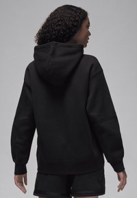 Sweatshirt preto com capuz, de corte relaxado, com punhos canelados e uma textura suave. Apresenta um design liso, sem impressões ou logótipos visíveis.