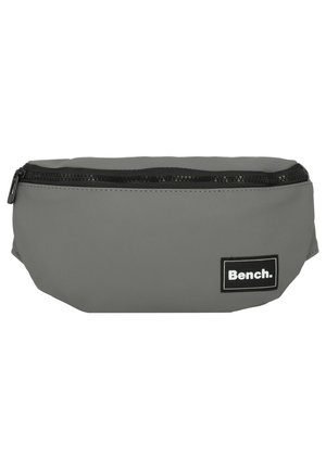 Sac banane en tissu gris avec fermeture éclair noire et patch logo de la marque Bench sur le devant côté droit.
